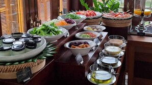 Un bufé con diversos platos y bebidas, dispuesto cerca de amplios ventanales con vista a un edificio tradicional.
