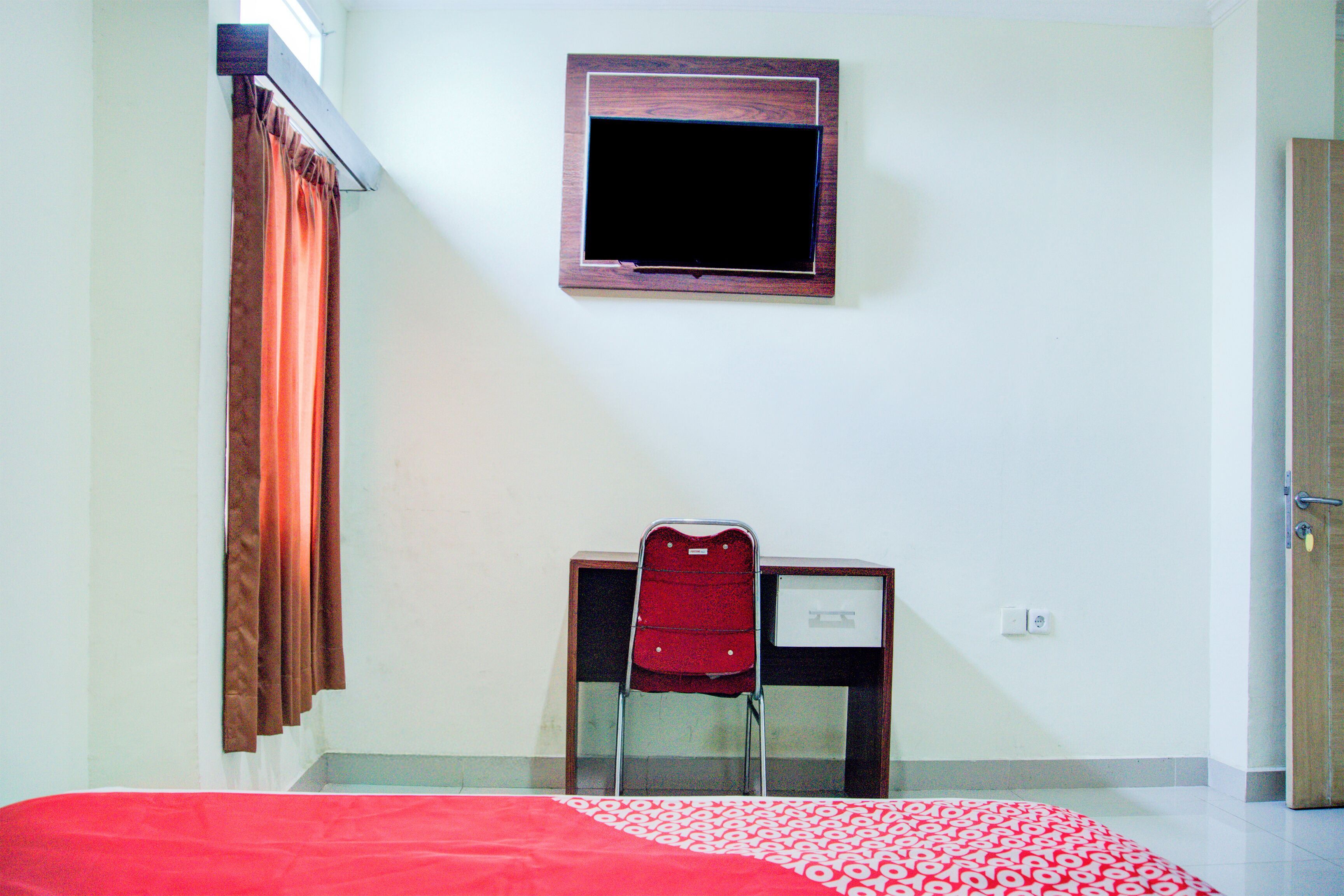 A room with a bed, a desk, a chair, a window with curtains, and a door.