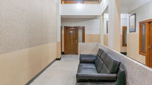 A hallway with a leather sofa, a wooden door, and a balcony. - Hotel O Ilir Barar I Near Rumah Sakit Islam Siti Khadijah Formerly Maleo Hotel (Palembang)