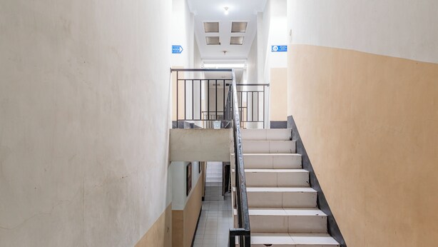A staircase with a handrail, a tiled floor, and a wall with a door at the top. - Hotel O Ilir Barar I Near Rumah Sakit Islam Siti Khadijah Formerly Maleo Hotel (Palembang)