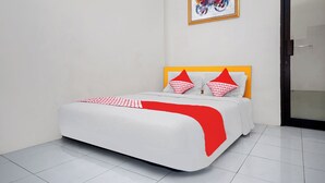 A neatly made bed with a white and red bedspread, a wooden headboard, and matching pillows. - Hotel O Ilir Barar I Near Rumah Sakit Islam Siti Khadijah Formerly Maleo Hotel (Palembang)