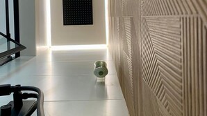 A modern hallway with a sleek, minimalist design, featuring a patterned wall, a recessed ceiling light, and a small decorative object on the floor. - Exterior Studio 3rd floor (Málaga)