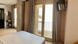 A bedroom with a bed, a bathroom with a sink and mirror, and a balcony with a view.