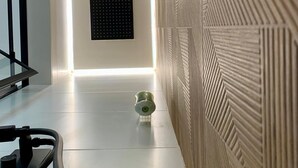 A modern hallway with a sleek, minimalist design, featuring a patterned wall, a recessed ceiling light, and a small decorative object on the floor.