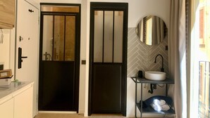 A modern bathroom with a black door, a white sink, and a mirror on the wall.