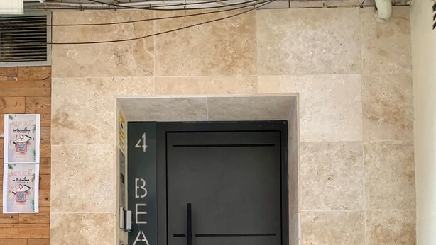 A modern black door with the number 4 and the word "BEATAS" on the wall to the left.