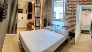 A bedroom with a bed, a desk, a chair, and a window.