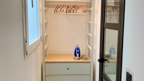 Un dressing avec éclairage intégré, une tringle à vêtements et un banc doté de tiroirs de rangement.