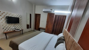 Een slaapkamer met een bed, een aan de muur bevestigde televisie, een kledingkast en een airconditioning.
