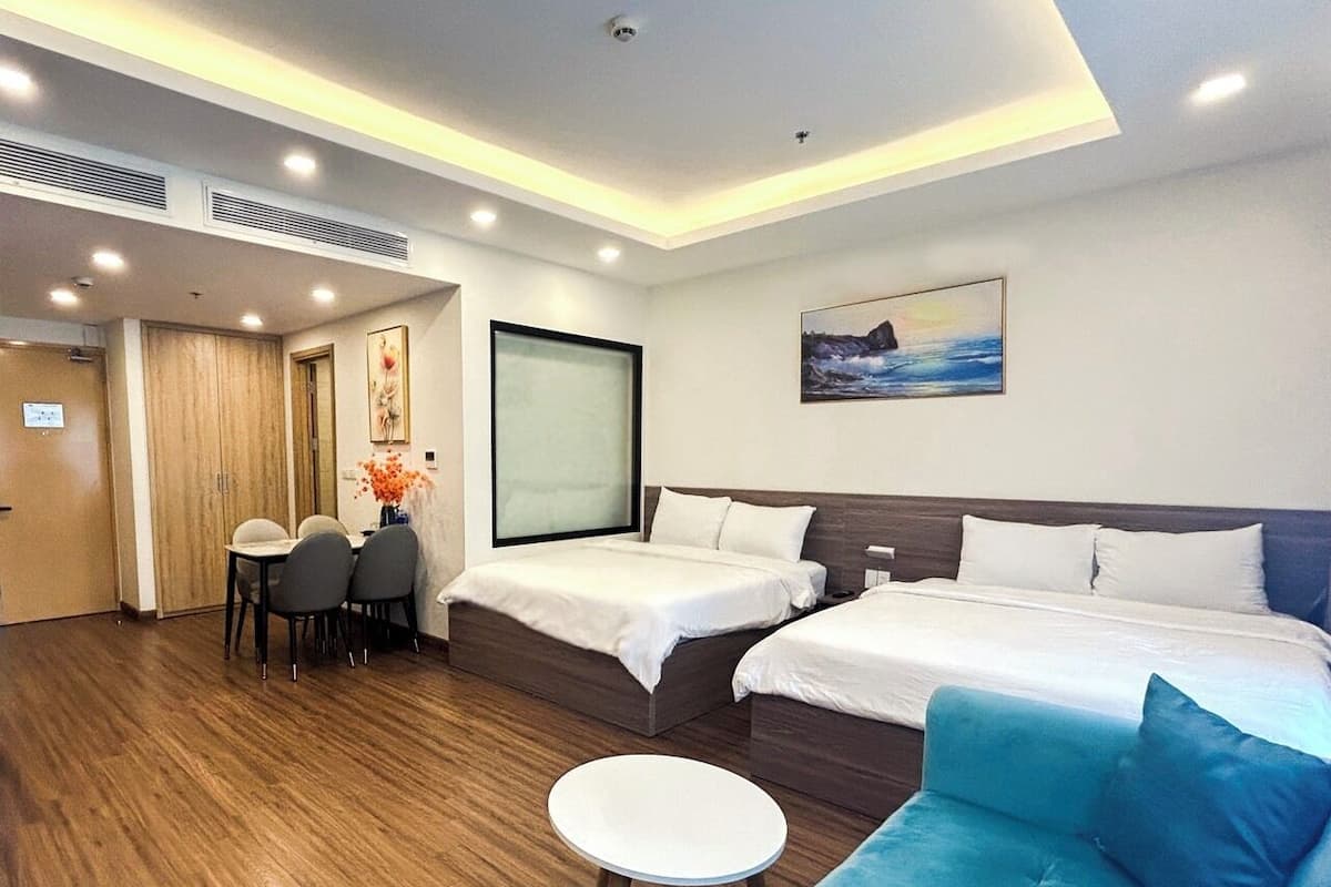 Habitación de hotel con dos camas, zona de comedor y vista al mar.