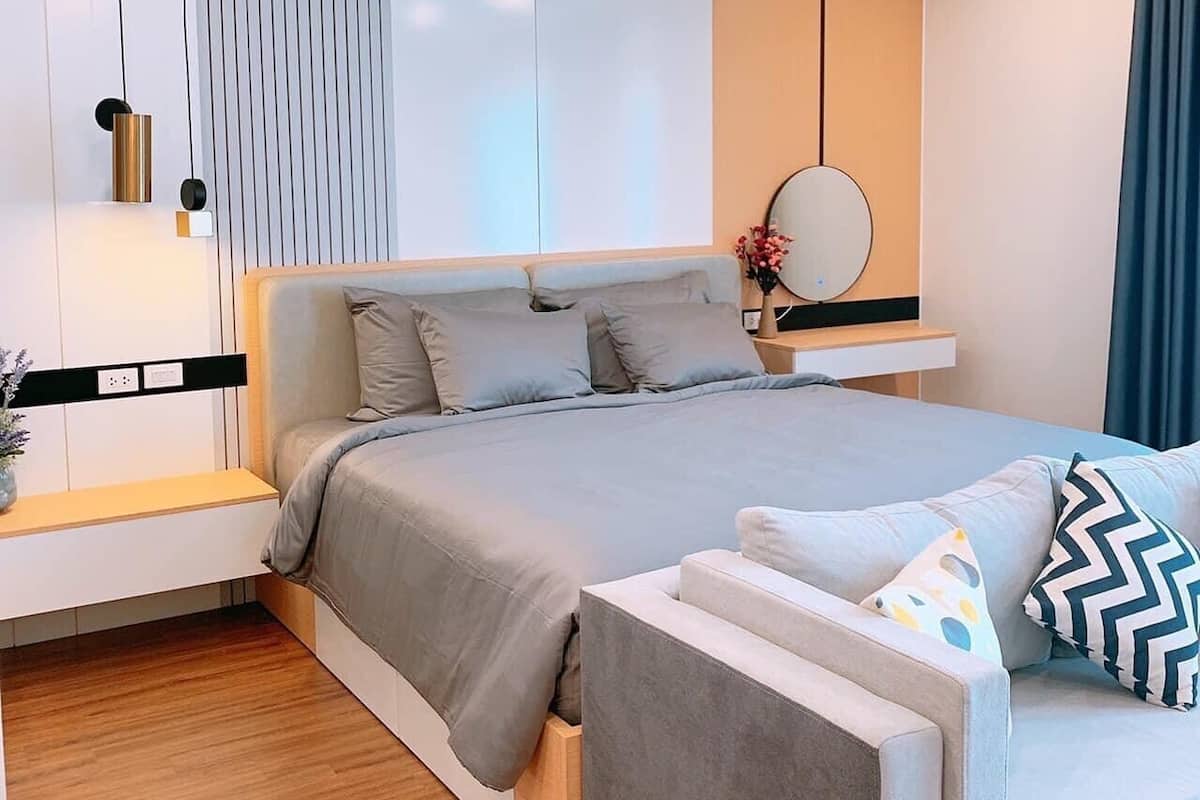 Un dormitorio moderno con una cama, mesitas de noche, un espejo y un sofá.