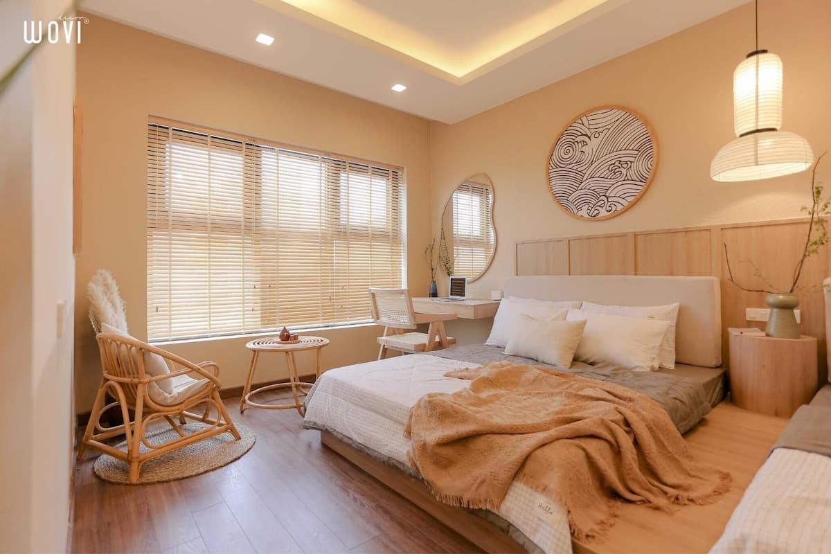 Un dormitorio con cama, mesita de noche, silla y un ventanal con persianas.