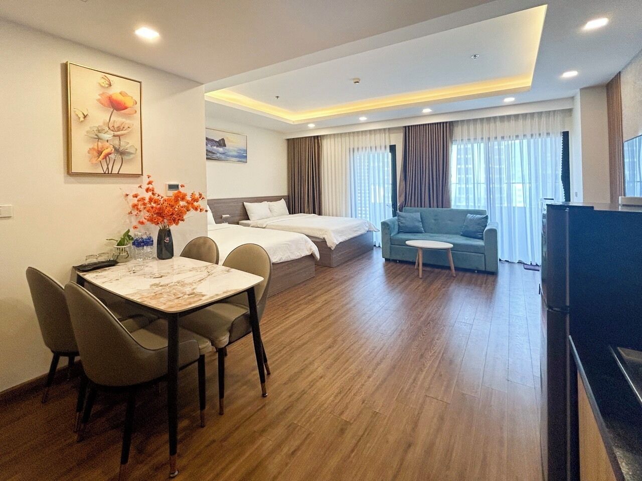 A hotel room with a dining area, a sofa, a TV, and a bed.