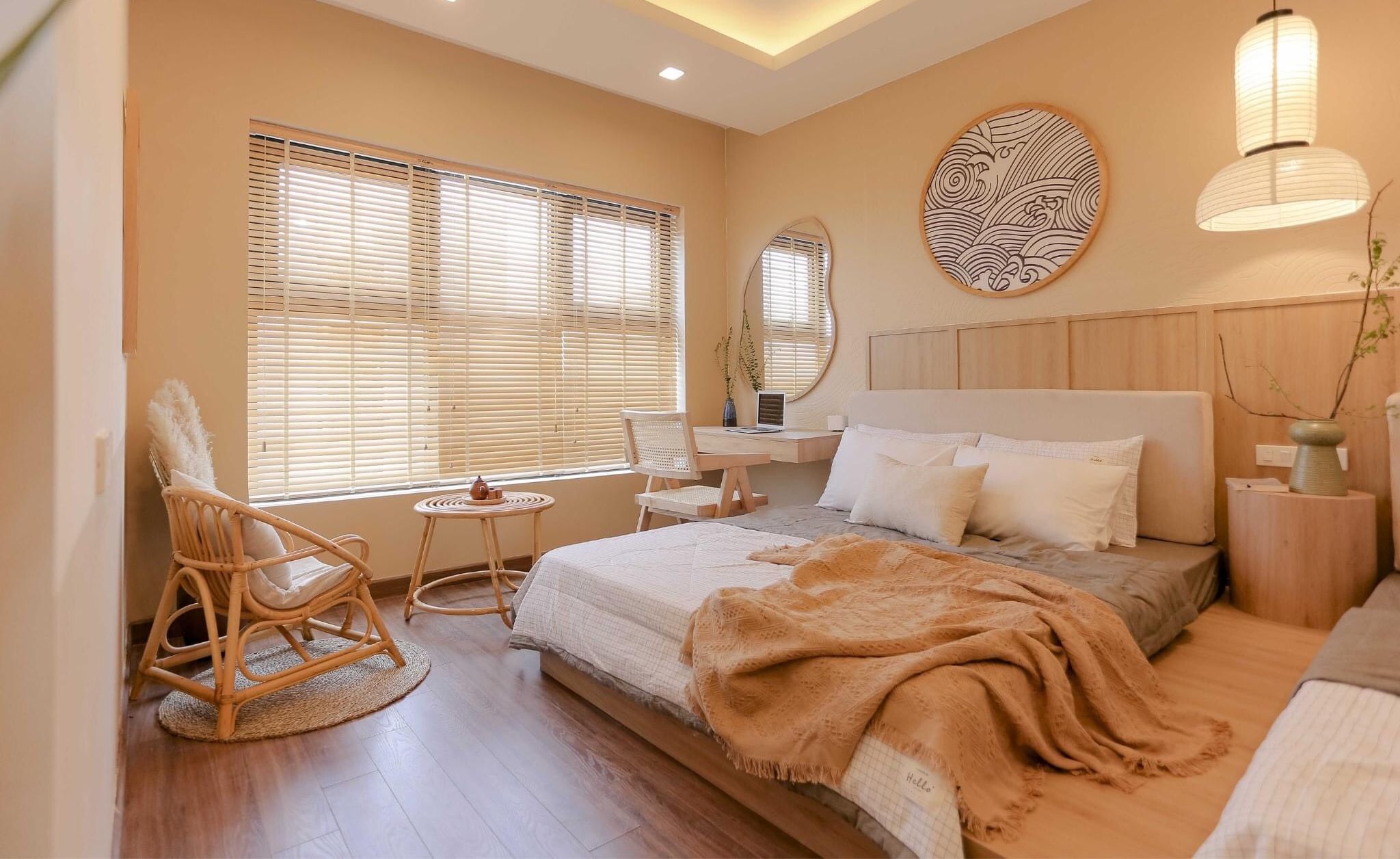 A bedroom with a bed, bedside table, chair, and a large window with blinds.