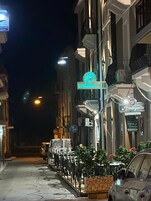 Vista nocturna de una calle con un letrero de neón que dice 'EMERELLA' y un restaurante llamado 'la Bodega'.