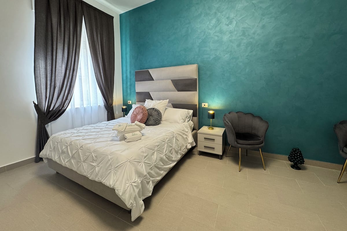 A bedroom with a bed, bedside tables, a chair, and a nightstand.