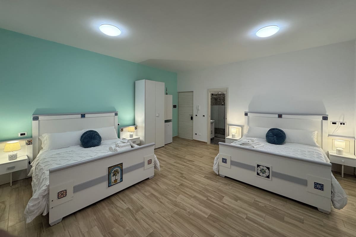 A twin bedroom with two beds, a wardrobe, a bathroom, and a ceiling light.