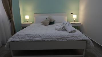 A hotel room with a bed, two bedside tables with lamps, a headboard, and a window with curtains.