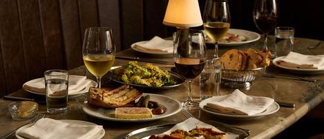 A dining table set with various dishes, glasses of wine, and a lamp.