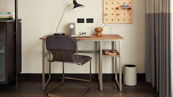 A modern office space with a desk, chair, lamp, clock, and wall-mounted storage.