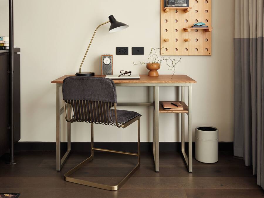A modern office space with a desk, chair, lamp, clock, and wall-mounted storage.