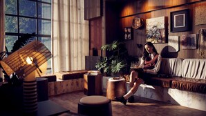 A cozy living room with a large window, wooden furniture, and a variety of decorative items on the walls. - Hotel Indigo Auckland by IHG (Auckland)
