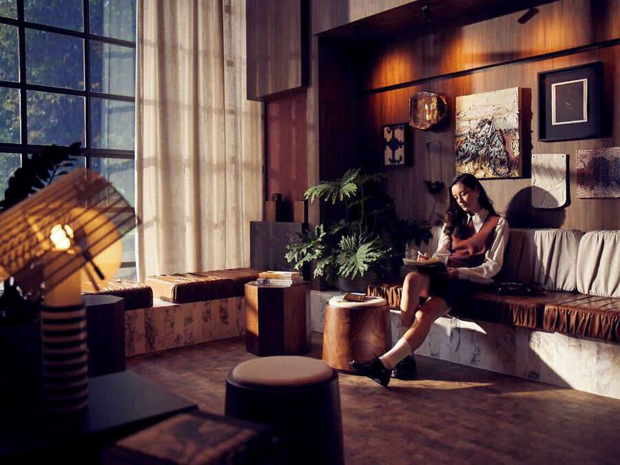 A cozy living room with a large window, wooden furniture, and a variety of decorative items on the walls.