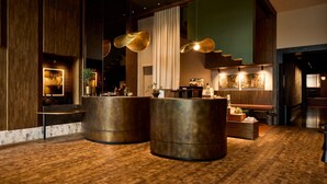A lobby with two large cylindrical reception desks, wooden flooring, and hanging pendant lights. - Hotel Indigo Auckland by IHG (Auckland)