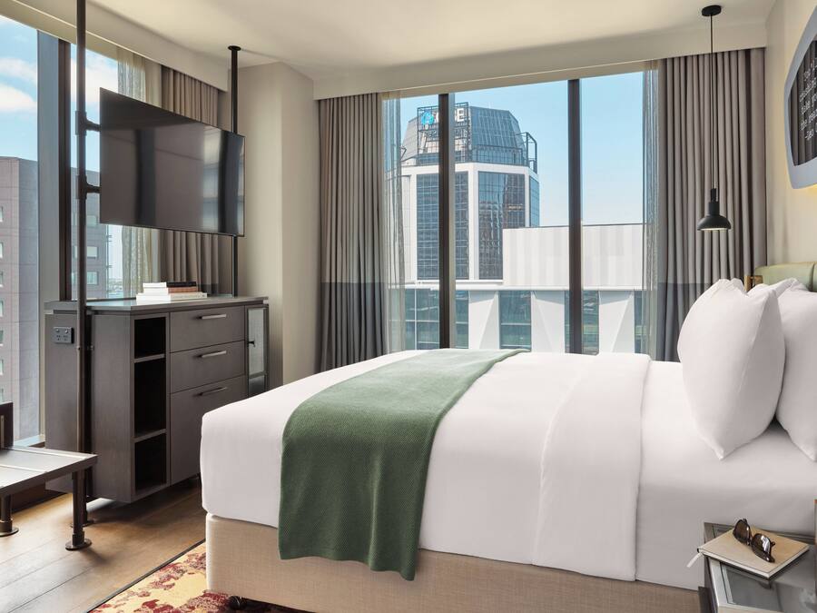 A modern hotel room with a large bed, a desk, and a TV.