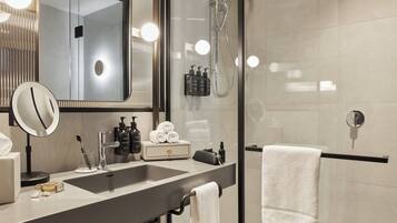 Une salle de bain moderne avec un grand miroir, deux lavabos, une douche et un porte-serviettes.