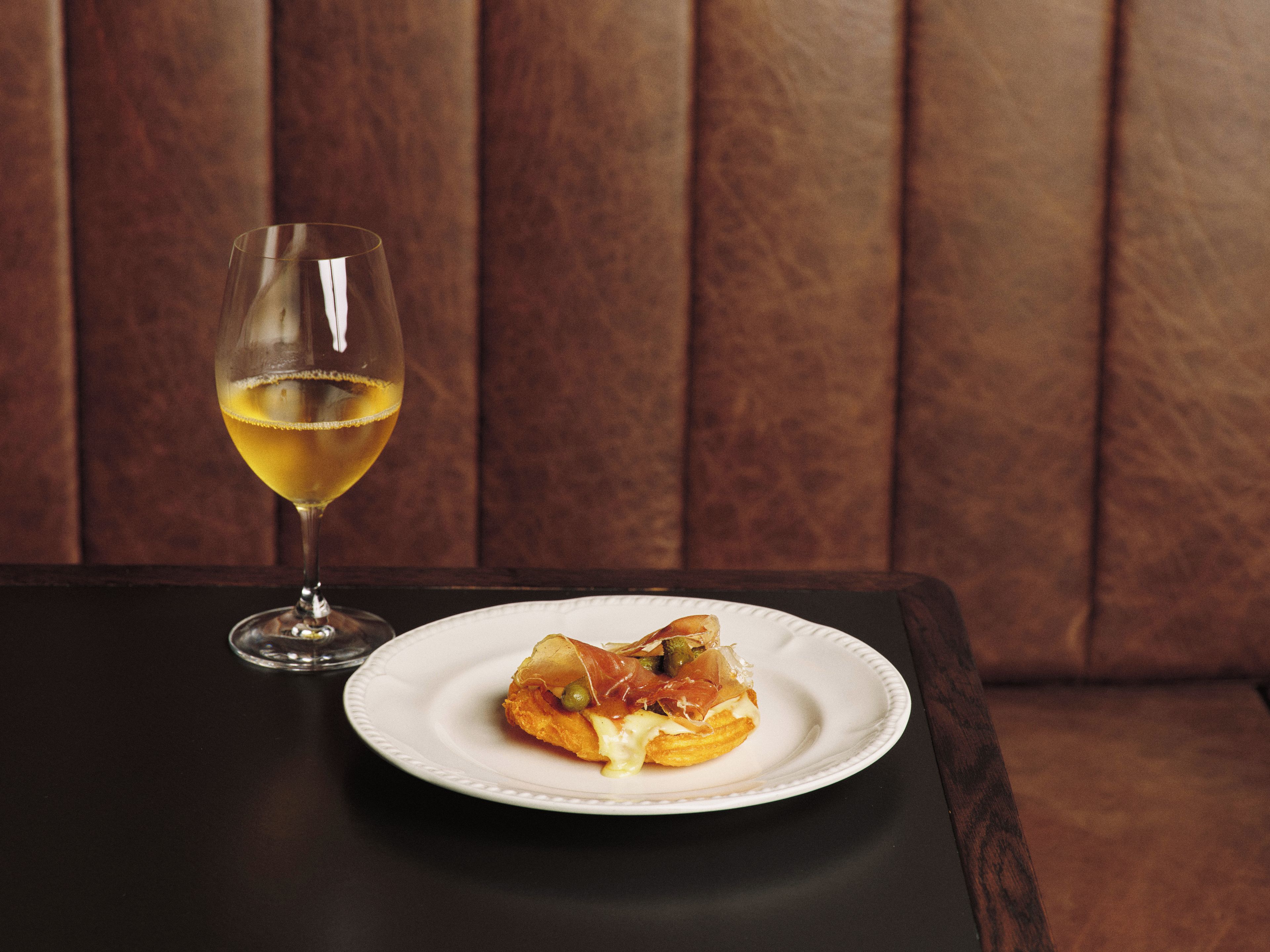A table with a plate of food and a glass of white wine.