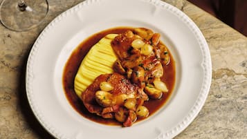 Ein Teller mit Speisen, ein Glas Rotwein und eine Marmorplatte.