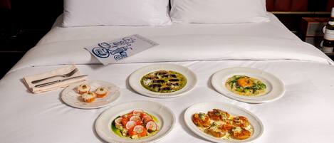 A neatly arranged bed with white linens, a pillow, and a menu on the bed.