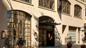 A hotel facade with large arched windows, a prominent entrance with a glass door, and signage for 'MACDONALD HALLIGAN MOTORS LTD.' - Hotel Indigo Auckland by IHG (Auckland)