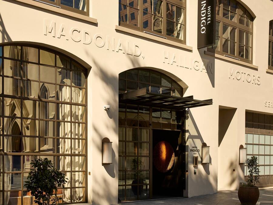 A hotel facade with large arched windows, a prominent entrance with a glass door, and signage for 'MACDONALD HALLIGAN MOTORS LTD.'
