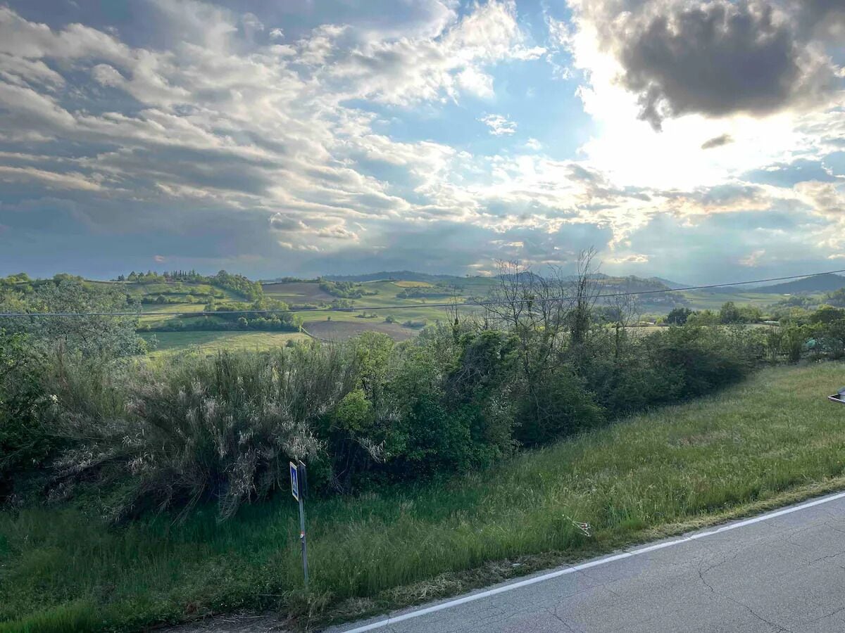 Ländliche Landschaft mit einer Straße, Grünflächen und Hügeln in der Ferne.