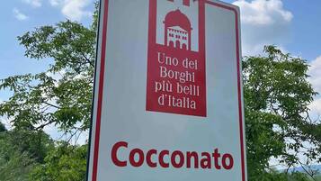 A sign with the text "Cocconato" and a symbol of a building with a dome, indicating a historical or cultural site.