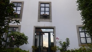 A building with a central entrance, two windows on either side, and a parking sign.