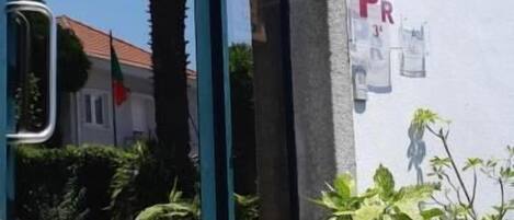 Entrada de un edificio con puerta de cristal, escalones y plantas en macetas.