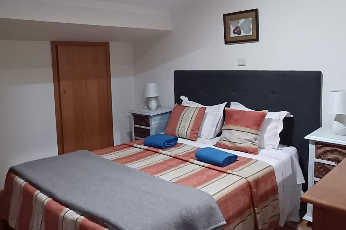Une chambre à coucher avec un lit, une table de chevet, une lampe et un tableau encadré au mur.
