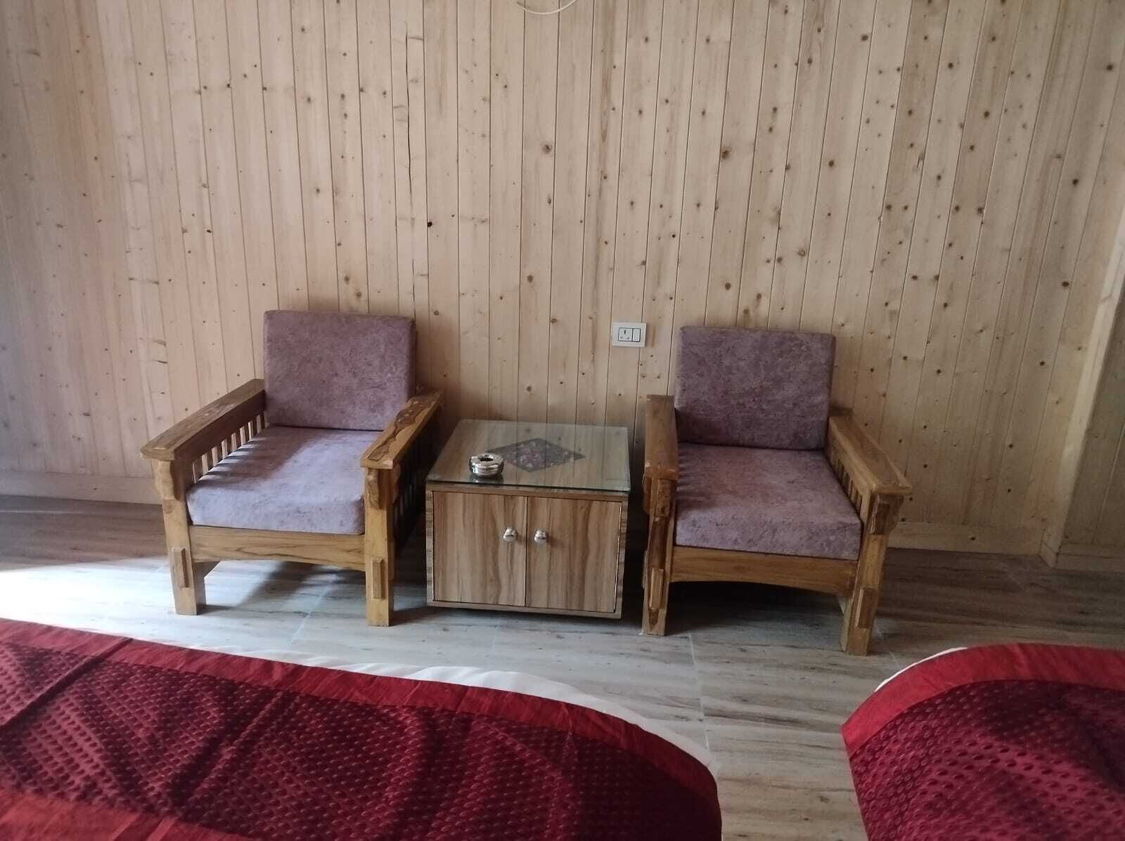 A wooden-paneled room with two wooden armchairs and a small wooden table.