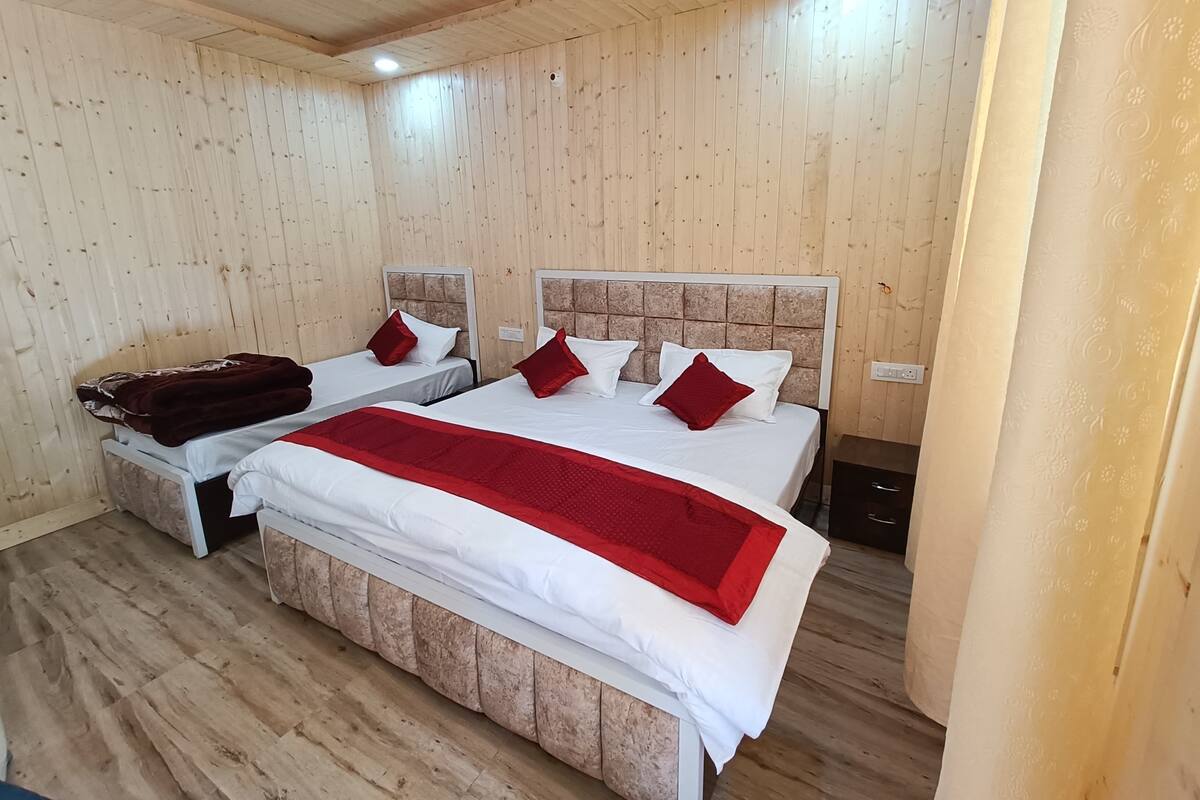 Habitación con paneles de madera y dos camas, cada una con cabecera y almohadas.