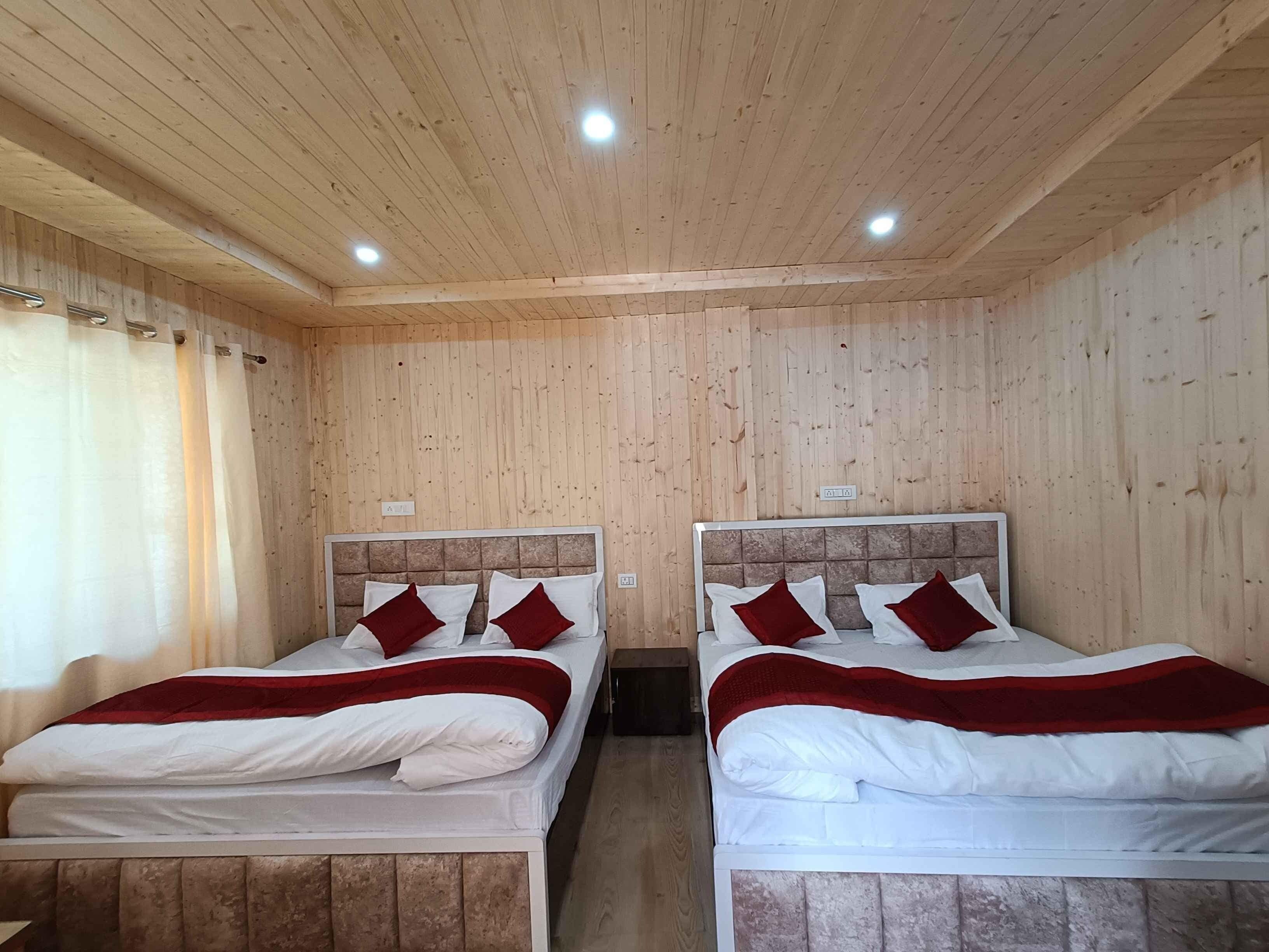 Une chambre avec deux lits, des murs en bois et des luminaires au plafond.