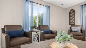 A room with two brown leather sofas, a small table with a plant, and a decorative wall piece.