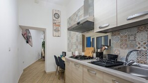 Une cuisine moderne équipée d’une cuisinière à gaz, d’un évier et de meubles de rangement de couleur claire. On y trouve également une horloge murale décorative et un pare-feu décoratif.