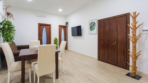 Un coin repas avec une table et des chaises en bois, un téléviseur fixé au mur et une grande armoire en bois.