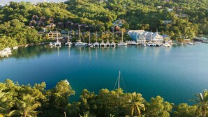 A marina with boats docked, surrounded by lush greenery and hills.