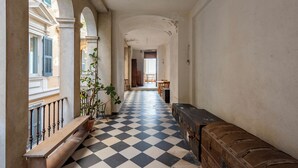 Un couloir avec un sol à carreaux, un banc et une plante en pot.