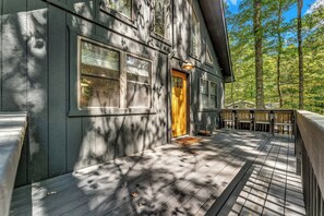 A wooden house with a porch, a door, and a window.