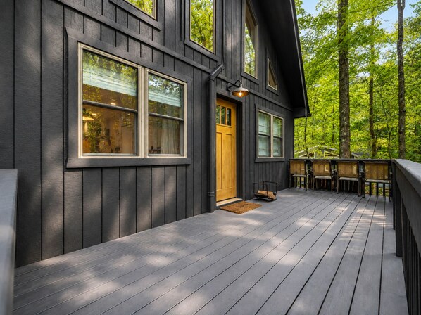 A wooden deck with a built-in bench area, a door, and windows.